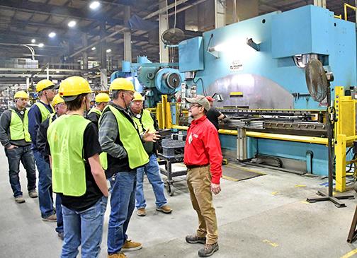 Tour guide Tom Ernstmeyer, right, answers a question from one of the members of his tour group as it pauses before a 700 ton press on the floor of the Case IH factory in Grand Island. 