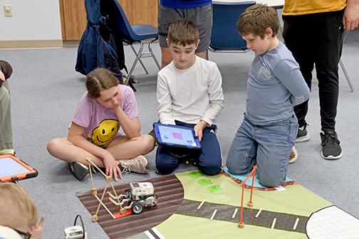One of the many challenges students at Hamilton County 4-H faced at Lego Robotics was to put in the right measurements to steer their robots around obstacles. From left, Lillie Land, Cody Paton and Dalton Land watch as their robot attempts to navigate through the course.