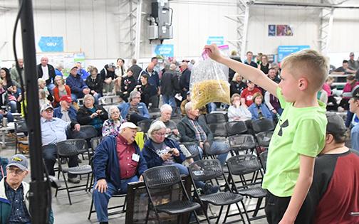 Young Colton McCartney holds up an auction item in front of a large crowd gathered Saturday morning at the Farr Building